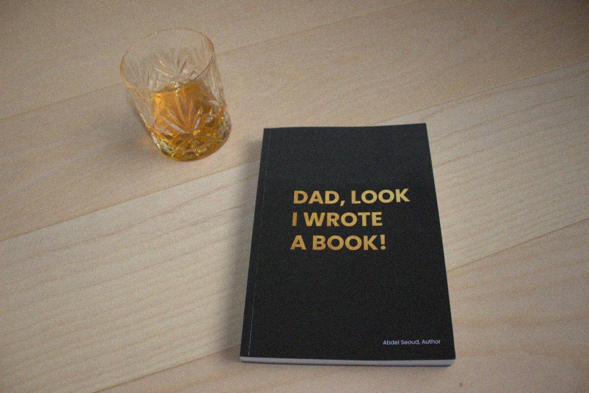 The only copy of Dad, Look - I Wrote A Book! on a wooden table next to a glass of whisky